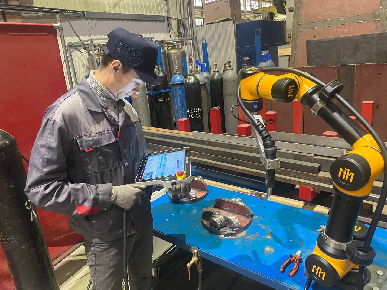 Оператор настраивает коллаборативный робот для сварки запорной арматуры